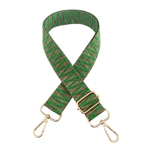 Close-up of green woven bag strap with golden geometric patterns and metal hooks