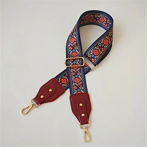 Close-up of ethnic style embroidered strap with gold lobster clasps and red leather details