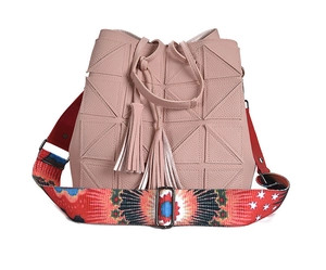 Detail of light pink bucket bag with geometric triangles, dual tassels and colorful strap