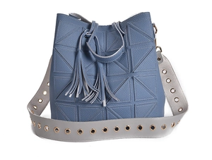 Detail view of blue bucket bag with geometric quilting and wide grey eyelet strap