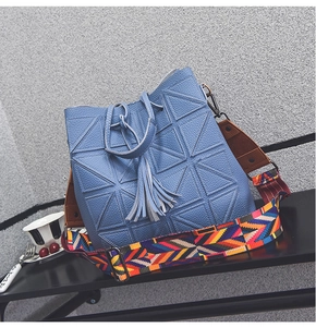 Close-up of blue pebbled leather bucket bag with geometric patterns and fringe tassels