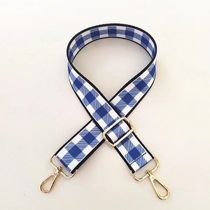 Detail of adjustable blue and white gingham bag strap with polished gold hardware