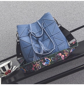 Detail of blue pebbled leather bucket bag with vibrant butterfly print wide shoulder strap