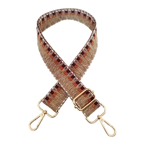Detail of wide woven strap with geometric patterns and light gold metal swivel hooks