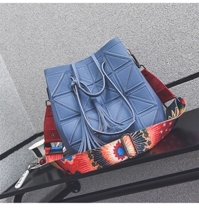Detail of blue bucket bag with geometric quilting and floral pattern wide strap