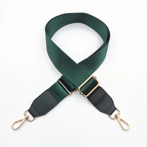 Macro detail of dark green nylon bag strap with adjustable gold buckle and metal lobster clasps