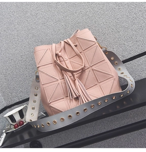 Detail of pink bucket bag with geometric triangles, tassels and grey eyelet strap