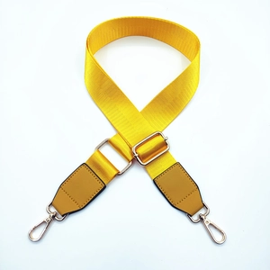 Detail of adjustable yellow nylon bag strap with leather ends and gold metal buckles