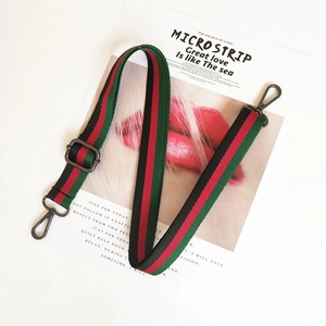 Detail of adjustable green and red striped nylon bag strap with matte black hardware