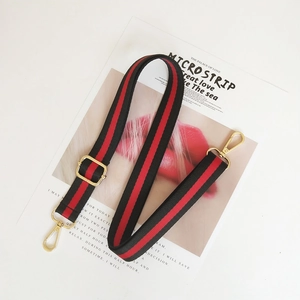 Detail of adjustable canvas bag strap with black and red stripes and gold lobster clasp