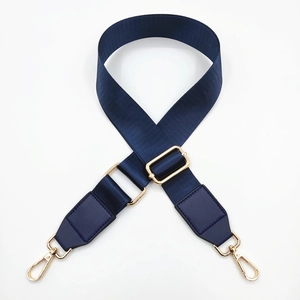 Close-up of navy blue nylon bag strap with golden metal swivel hooks and buckles