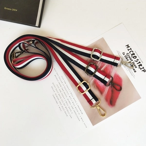 Close-up of adjustable striped canvas bag straps with gold, silver and gunmetal hardware