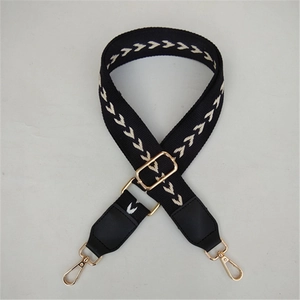 Detail of black and white woven strap with golden metal buckle and leather ends