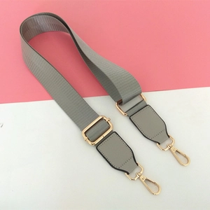 Detail of adjustable gray nylon strap with gold metal buckles and gray leather accents