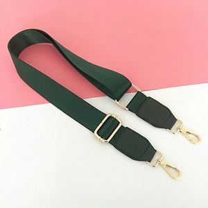 Close-up of dark green nylon strap with adjustable gold buckles and lobster clasps