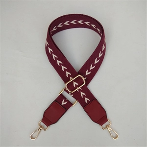 Detail of burgundy geometric wide bag strap with gold metal buckles and adjustable slider