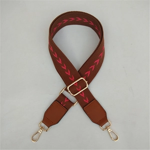 Close-up of adjustable woven chevron strap with brown leather and gold metal hooks