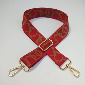Macro view of adjustable red shoulder strap with geometric pattern and gold metal hooks
