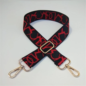 Detail of adjustable black and red geometric embroidered nylon strap with gold buckles