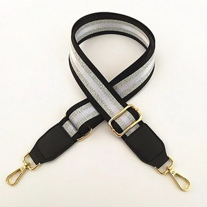 Detail of adjustable embroidered bag strap with silver glitter stripes and gold hooks