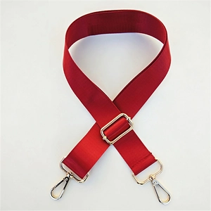 Detail of adjustable dark red nylon bag strap with polished gold-tone metal hardware