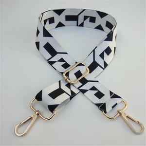 Detail of adjustable black and white geometric bag strap with polished gold metal hooks