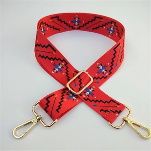 Close-up of ethnic style wide guitar strap with red geometric pattern and gold hardware