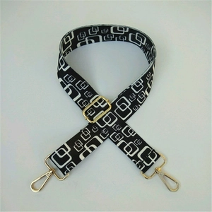 Macro detail of adjustable wide strap with black and white geometric patterns and gold clips