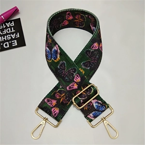 Close-up of wide green fabric shoulder strap with butterfly pattern and gold metal hooks
