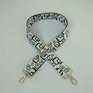Detail of adjustable black and white geometric pattern bag strap with gold metal hooks