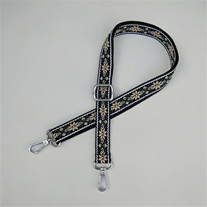 Close-up of ethnic embroidered bag strap with beige snowflake patterns and silver hooks