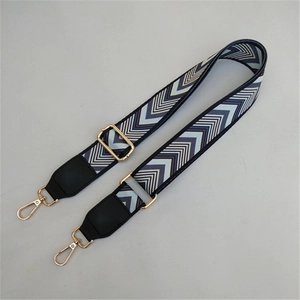 Detail of adjustable bag strap with blue chevron pattern and gold metal hardware