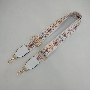Close-up of white ethnic floral embroidery strap with golden metal swivel hooks