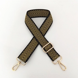 Close-up of adjustable nylon bag strap with yellow herringbone pattern and gold buckles