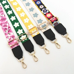 Detail of adjustable floral woven shoulder straps with gold metal hooks and leather tabs