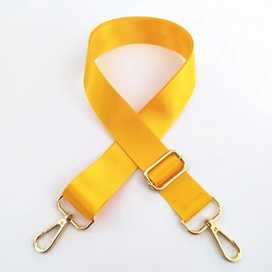 Close-up of thick yellow nylon bag strap with polished gold metal lobster clasps