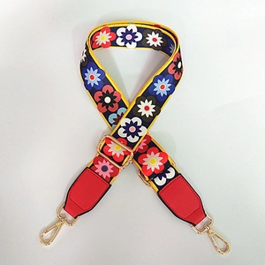 Detail of adjustable wide canvas strap with colorful floral embroidery and gold metal hooks