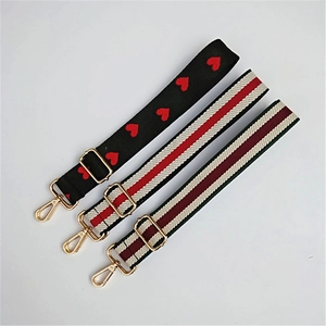Detail of adjustable woven bag straps with gold metal hooks and heart patterns