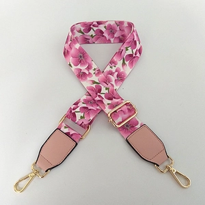 Macro view of adjustable fabric shoulder strap featuring pink cherry blossom pattern and gold hooks