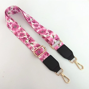 Close-up of adjustable pink floral canvas strap with gold metal buckles and leather ends