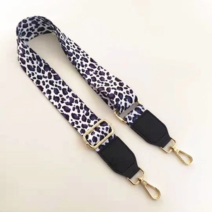 Detail of adjustable purple leopard print bag strap with golden metal hooks and black leather