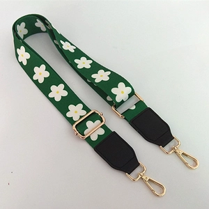 Close-up of adjustable green floral strap with white daisies and gold metal hooks