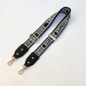 Close-up of adjustable woven shoulder strap with gold metal buckles and leather ends