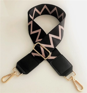 Detailed view of adjustable wavy pattern bag strap with polished gold-tone hardware buckles