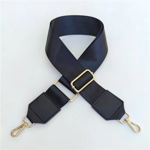 Macro detail of adjustable black woven wide shoulder strap with gold metal swivel hooks