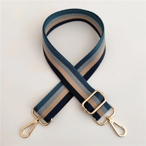Detail of adjustable striped woven bag strap with navy and beige colors and gold metal buckles