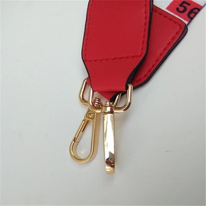 Detail of adjustable woven bag strap with red leather finish and gold lobster clasp
