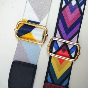 Close-up of wide woven bag straps with geometric patterns and gold metal buckles