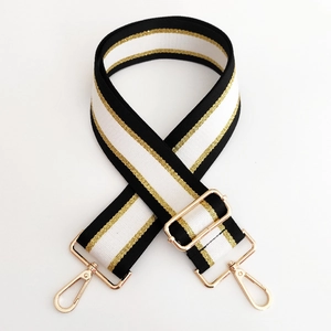 Adjustable black and white striped shoulder strap with gold metallic thread and buckles