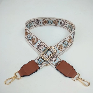 Detail of adjustable ethnic style wide strap with floral embroidery and golden metal hooks
